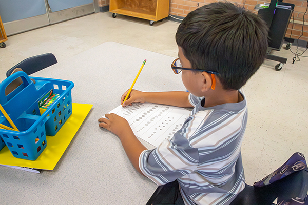 A little boy writes on a worksheet