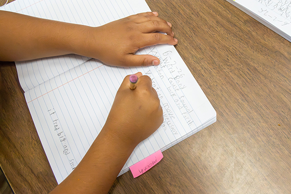 A girl writes on notebook paper