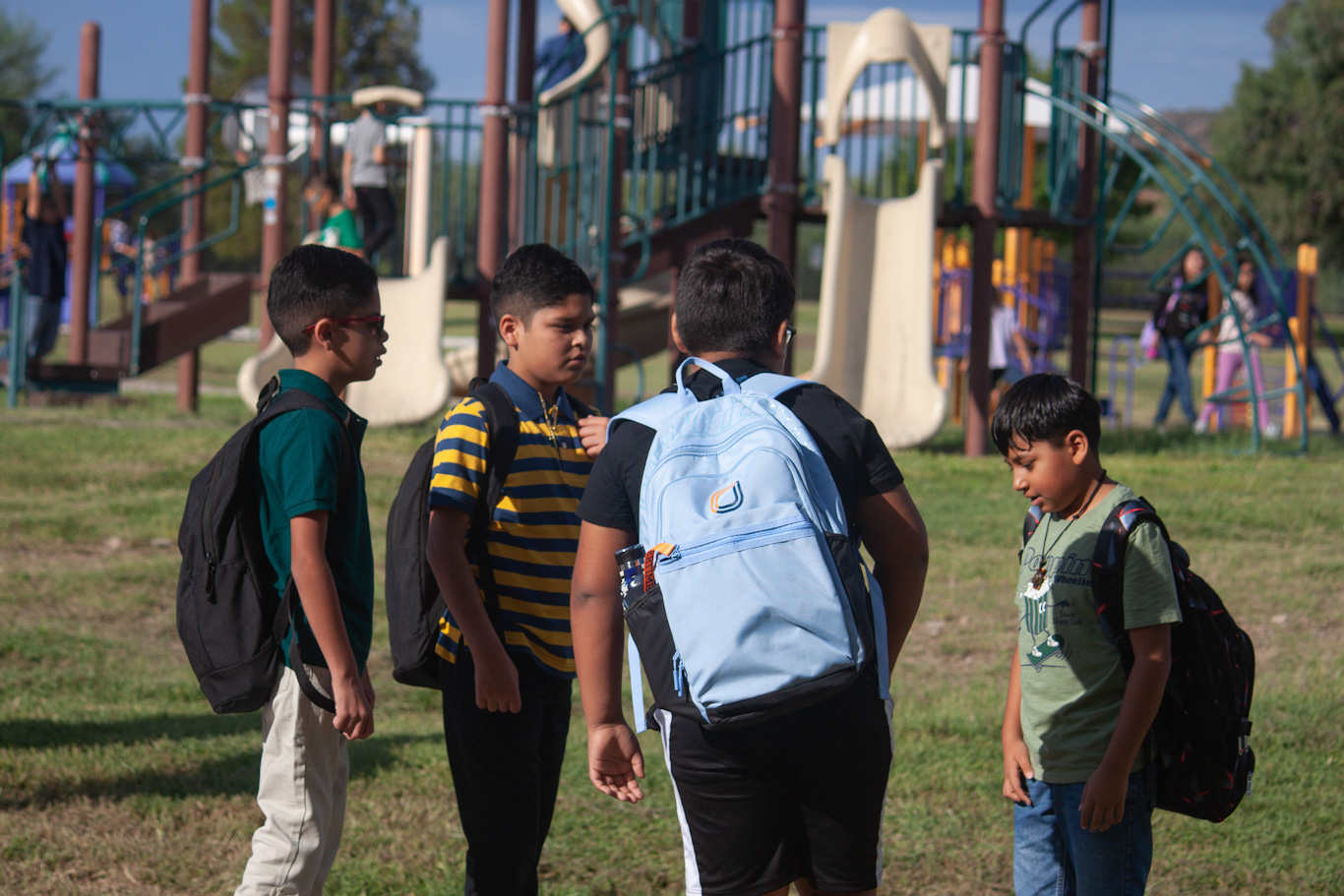 Four boys stand by the playground before school